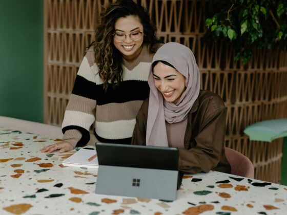 Two women sitting at a table with a laptop