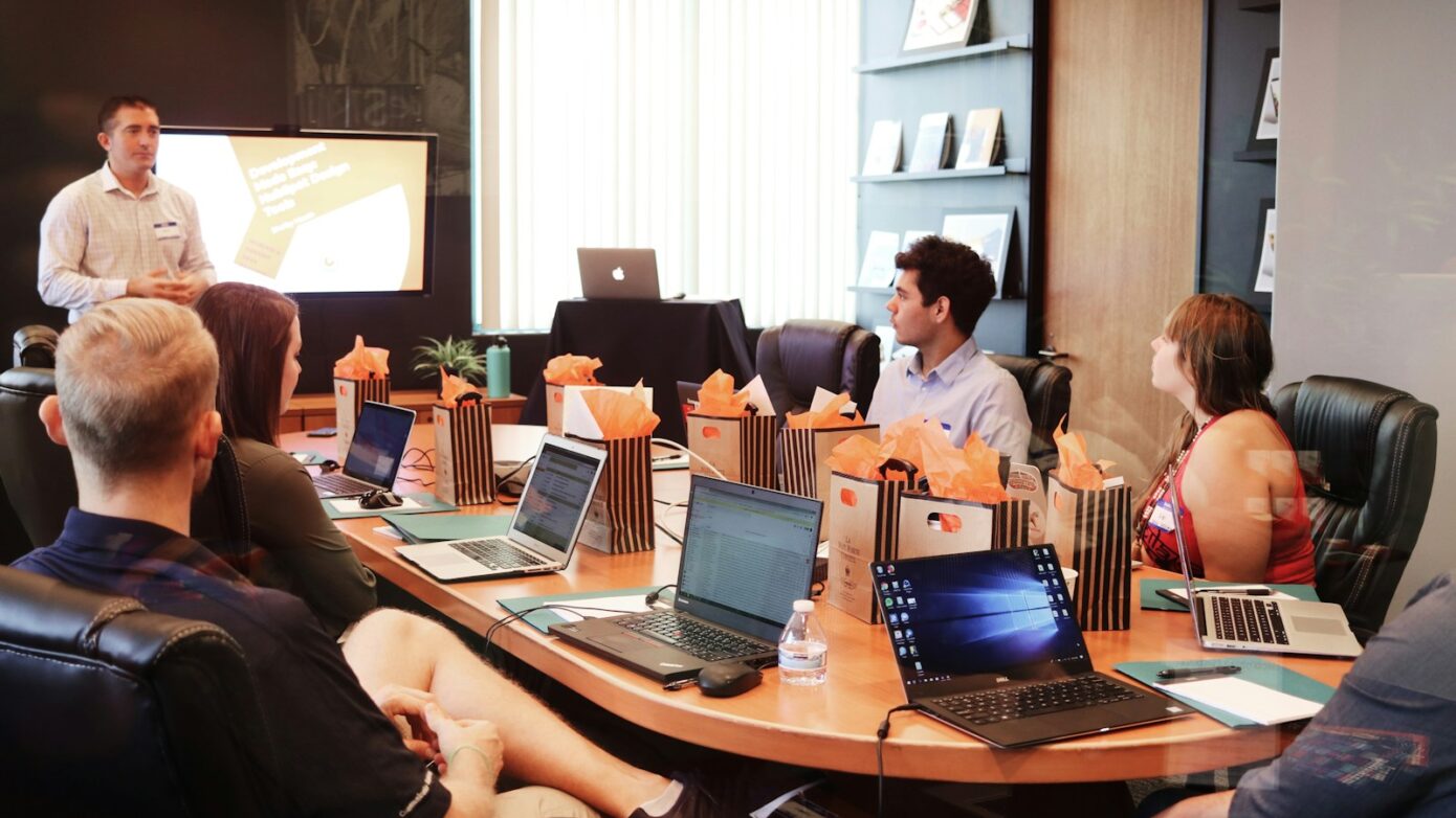 man standing in front of people sitting beside table with laptop computers