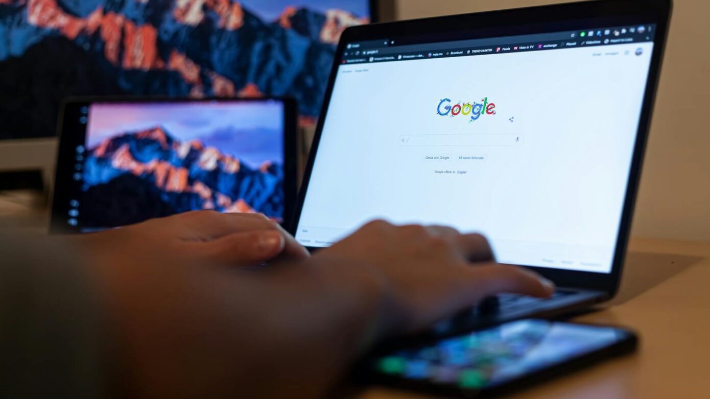 Hands typing on a laptop with Google on screen, in a remote work setup in Milan, Italy.