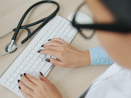 Doctor typing on keyboard with stethoscope nearby